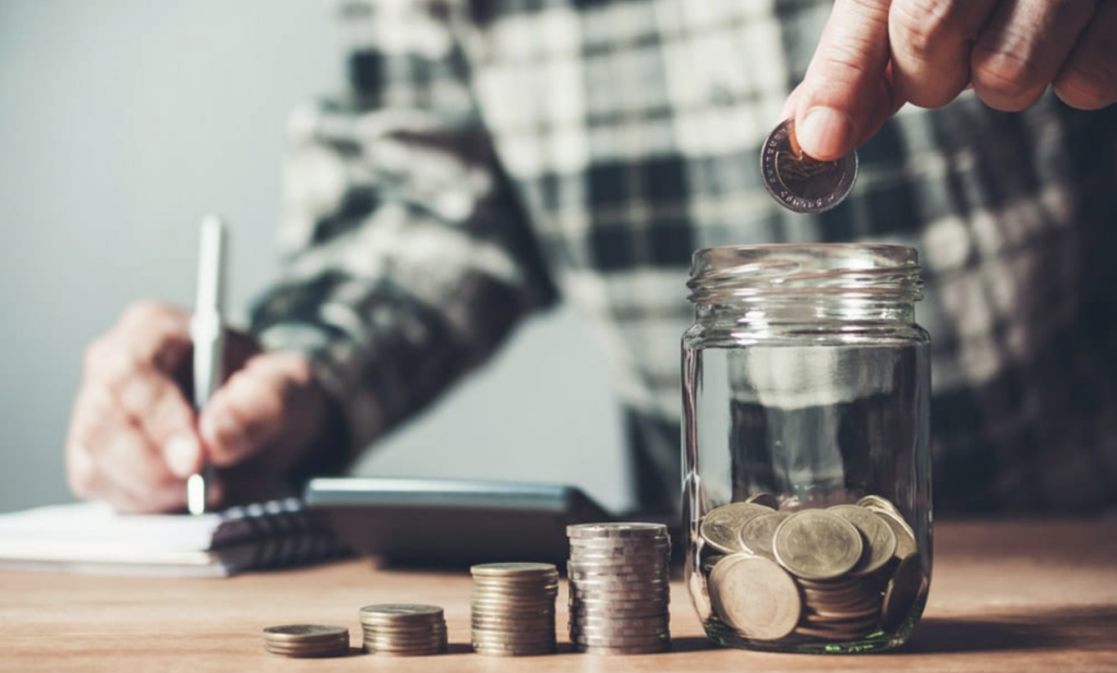 Person counts coins and places them in a jar.