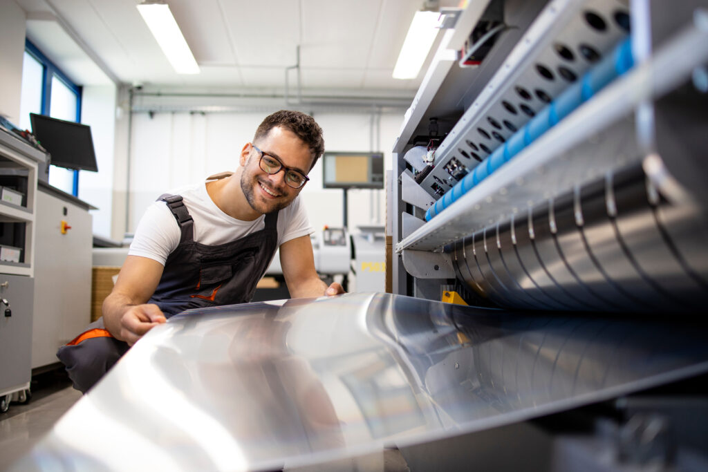 Worker working on computer to plate machine in a flexographic printing shop.