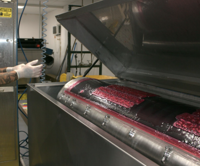 Worker in safety goggles pours liquid photopolymer resin.